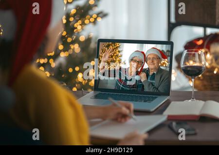 Les couples seniors discutent avec leur fille adulte en utilisant un ordinateur portable dans le salon décoré pour Noël. Banque D'Images