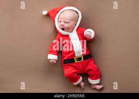 Fille de nouveau-né vêtue de costume du père noël bâillements fatigués. Banque D'Images