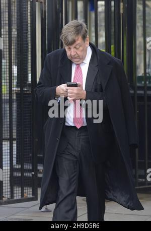 John Whittingdale MP (con: Maldon) sur son téléphone mobile, quittant Palriament, décembre 2021 Banque D'Images