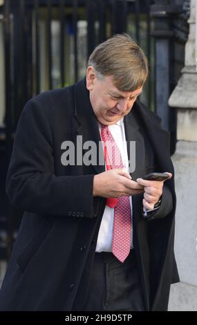 John Whittingdale MP (con: Maldon) sur son téléphone mobile, quittant Palriament, décembre 2021 Banque D'Images