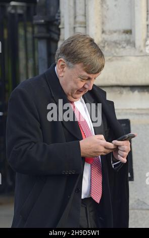 John Whittingdale MP (con: Maldon) sur son téléphone mobile, quittant Palriament, décembre 2021 Banque D'Images