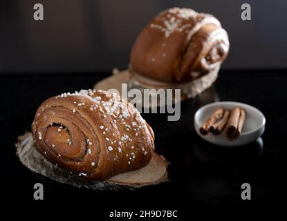 Helsinki / Finlande - 4 DÉCEMBRE 2021 : gros plan des petits pains à la cannelle finlandais traditionnels sur des dessous de verre en bois.Bâtonnets de cannelle. Banque D'Images