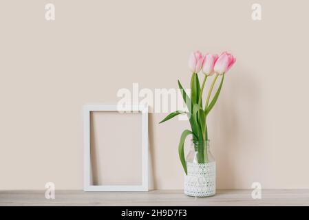 Modèle dans Un cadre blanc avec Une tulipe rose dans un pot en verre avec dentelle.Espace pour le texte Banque D'Images
