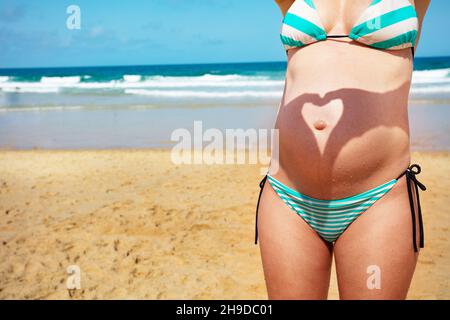 Le ventre de la femme enceinte avec un geste d'ombre du cœur Banque D'Images