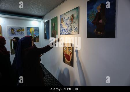 Les Palestiniens visitent une exposition d'art dans le cadre d'une campagne de sensibilisation à la violence à l'égard des femmes, dans la bande de Gaza, le 6 décembre 2021. Banque D'Images