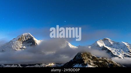 Étoiles illuminant les sommets enneigés de l'Eiger, du Monch et de la Jungfrau dans le brouillard nocturne, Mannlichen, canton de Berne, Suisse Banque D'Images