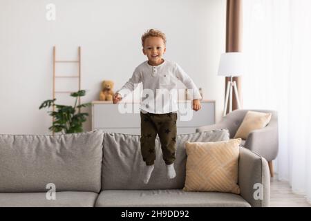 Joyeux petit garçon américain d'Afrique Jumping s'amuser à la maison Banque D'Images