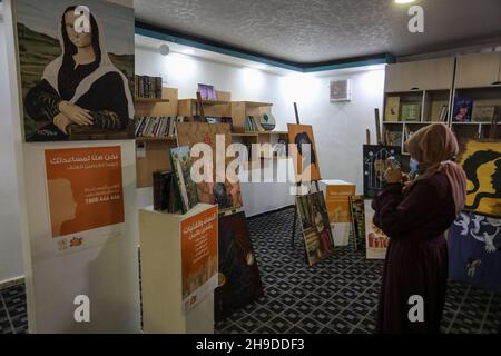 Les Palestiniens visitent une exposition d'art dans le cadre d'une campagne de sensibilisation à la violence à l'égard des femmes, dans la bande de Gaza, le 6 décembre 2021. Banque D'Images