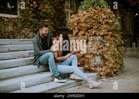 Beau jeune couple assis sur les escaliers extérieurs un jour d'automne Banque D'Images