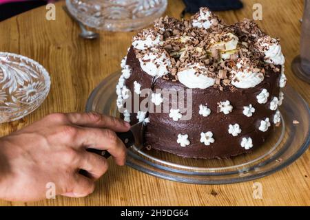 Gâteau au chocolat avec crème fouettée et bananes en cours de coupe Banque D'Images
