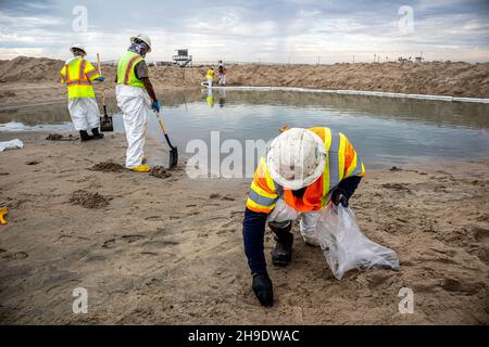 Une équipe de nettoyage nettoie les gisements de pétrole et de goudron, et se hale d'une berme construite pour empêcher l'huile de s'écouler dans la rivière Santa Ana, qui normalement Banque D'Images