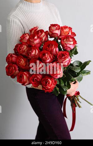 Bouquet luxuriant de roses rouges.Idée cadeau pour la Saint-Valentin.Fleuriste femme tenant un grand bouquet frais.Présent d'un bouquet de vingt fleurs longues. Banque D'Images