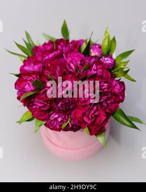 Composition de fleurs rondes de fleurs roses dans une boîte-cadeau cylindrique.Vue de dessus des roses rouges, plat.Bouquet de fuchsia brillant sur fond gris.Valentin Banque D'Images