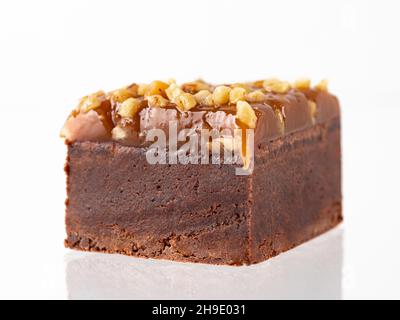 Gâteau au chocolat au brownie isolé sur blanc.Taille de la morsure marron chocolat humide avec garniture caramel et cacahuètes, isolé sur fond blanc avec passe-cheveux. Banque D'Images