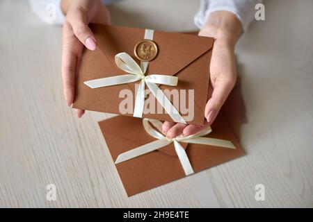 Chèque-cadeau, chèque-cadeau ou remise à la main de la femme. Photo en gros plan de l'enveloppe d'invitation avec ruban et sceau de cire, chèque-cadeau, mariage Banque D'Images