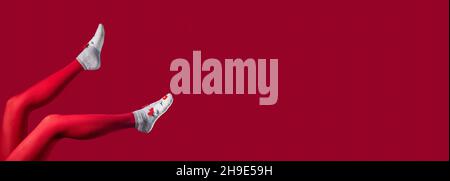 Banderole rouge de Noël avec jambes pour femmes en collants et chaussettes d'hiver sur fond avec espace pour le texte. Banque D'Images