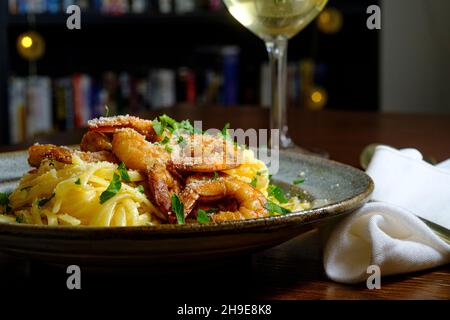 Fettuccine italienne alfredo avec crevettes cajun servi avec du vin blanc de pinot grigio Banque D'Images