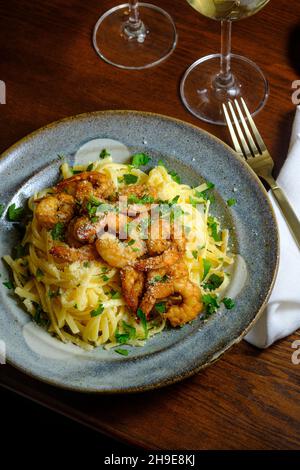 Fettuccine italienne alfredo avec crevettes cajun servi avec du vin blanc de pinot grigio Banque D'Images