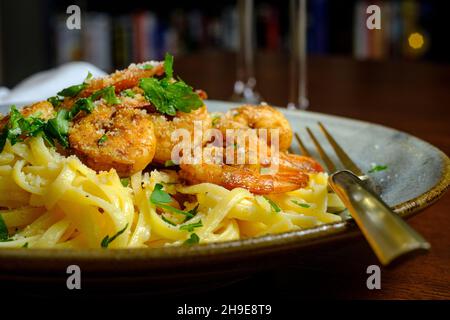 Fettuccine italienne alfredo avec crevettes cajun servi avec du vin blanc de pinot grigio Banque D'Images