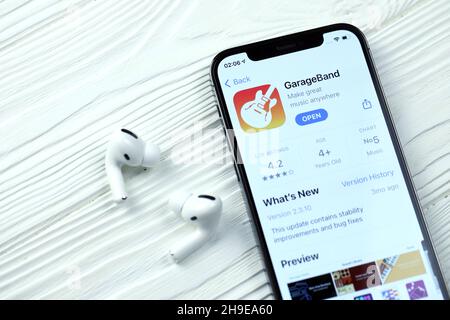 KHARKOV, UKRAINE - 5 MARS 2021 : icône GarageBand pour artistes et application de l'App Store sur iPhone 12 écran pro avec airpods pro sur blanc Banque D'Images