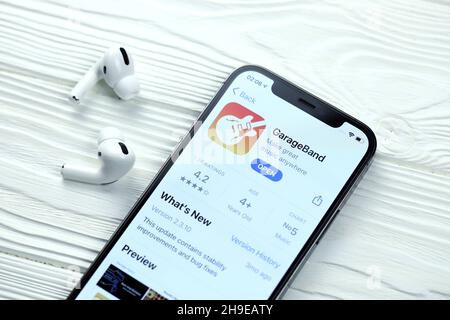 KHARKOV, UKRAINE - 5 MARS 2021 : icône GarageBand pour artistes et application de l'App Store sur iPhone 12 écran pro avec airpods pro sur blanc Banque D'Images