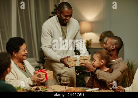 Portrait d'une famille afro-américaine heureuse échangeant des cadeaux tout en appréciant Noël à la maison ensemble Banque D'Images