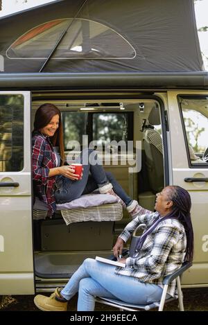 Diverses femmes voyageant près d'une camionnette au camping Banque D'Images