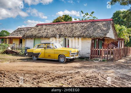 Une voiture jaune d'époque jaune d'Amérique travaillant comme un taxi attend pour un trajet devant un restaurant cubain local dans la ville de Vinales. Banque D'Images