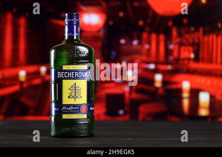 KHARKOV, UKRAINE - 14 FÉVRIER 2021 : bouteille de liqueur à base de plantes Becherovka sur table en bois avec intérieur de barre rouge sur fond.Production d'alcool élite Banque D'Images