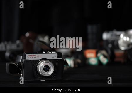 KHARKOV, UKRAINE - 27 AVRIL 2021: Smena 8m caméra de film et un autre vieux matériel photo rétro sur table en bois noir dans la chambre noire de photographe.PH Banque D'Images