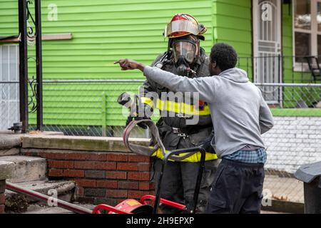 Detroit, Michigan - Un résident d'une maison en feu pointe dans le bâtiment alors qu'il parle à un pompier arrivant sur les lieux.L'incendie a endommagé une maison Banque D'Images