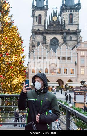 Prague, République tchèque.06e décembre 2021.Un homme portant un masque facial de protection prend un selfie avec un fond de l'arbre de Noël illuminé et de l'église notre-Dame avant Tyn à la place de la vieille ville de Prague.Le célèbre marché de Noël de la place de la Vieille ville de Prague est fermé en raison de la pandémie du coronavirus et des restrictions actuelles en matière d'état d'urgence en République tchèque.(Photo de Tomas Tkachik/SOPA Images/Sipa USA) crédit: SIPA USA/Alay Live News Banque D'Images