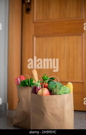 Des sacs de shopping de nourriture sont à la porte de la maison ou de l'appartement.Livraison de légumes et de fruits pendant la quarantaine et l'auto-isolement Banque D'Images