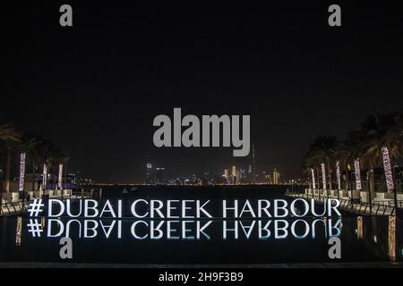 Les photos capturent une vue imprenable de nuit sur le panneau Dubai Creek Harbour reflété parfaitement dans les eaux calmes, avec la ligne d'horizon illuminée de la ville Banque D'Images