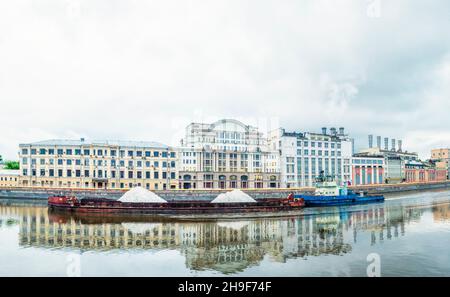 Une barge flotte sur la rivière Moskva sur le fond du remblai de Raushskaya Banque D'Images