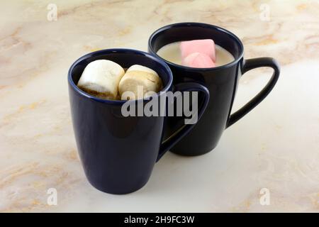 Boissons au chocolat chaud et au chocolat blanc chaud avec guimauves aux fraises blanches et roses en mugs bleues Banque D'Images