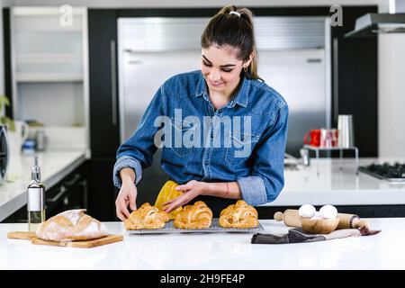 Jeune femme latine qui cuit des ingrédients de croissant dans la cuisine au Mexique en Amérique latine Banque D'Images