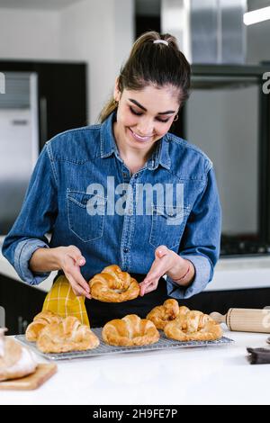 Jeune femme latine qui cuit des ingrédients de croissant dans la cuisine au Mexique en Amérique latine Banque D'Images