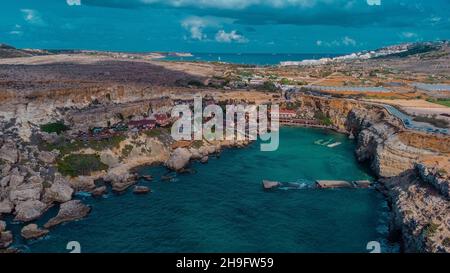 Drone aérien Panorama de baie pittoresque à Malte appelé Popeye village, ancien décor de film et maintenant une belle plage avec des maisons et des falaises émergeant fr Banque D'Images