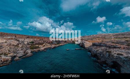 Drone aérien Panorama de baie pittoresque à Malte appelé Popeye village, ancien décor de film et maintenant une belle plage avec des maisons et des falaises émergeant fr Banque D'Images