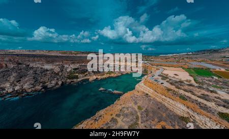 Drone aérien Panorama de baie pittoresque à Malte appelé Popeye village, ancien décor de film et maintenant une belle plage avec des maisons et des falaises émergeant fr Banque D'Images