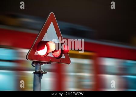 Le train de voyageurs se précipitant au-delà de l'avertissement d'arrêt la nuit.Nuit au passage à niveau du train. Banque D'Images