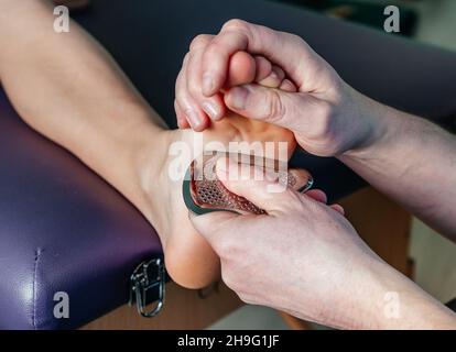 Physiothérapeute fixant la douleur plantaire au talon avec l'outil IASTM guasha Banque D'Images