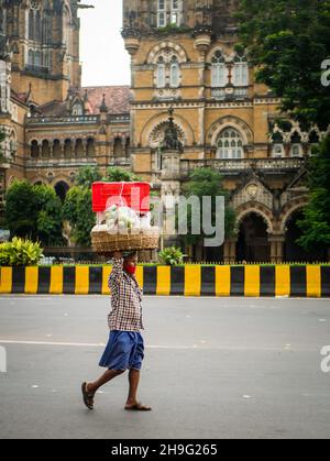 MUMBAI, INDE - 2 octobre 2021 : porteur non identifié portant un masque Covid-19 portant une charrette à fruits à la station CST, Mumbai Banque D'Images