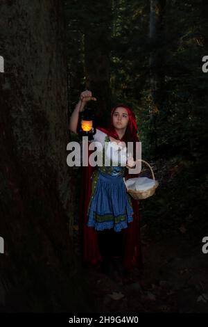 Petite cagoule rouge à la recherche du loup tout en marchant dans les arbres dans la Forêt Noire de l'Allemagne. Banque D'Images