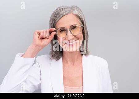 Photo de blanc froid coiffure dame aînée essayer des lunettes veste de protection isolée sur fond gris couleur Banque D'Images