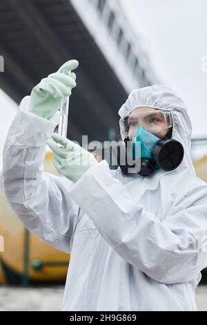 Portrait de la taille vers le haut de la scientifique féminine portant une combinaison de Hazmat collecte des échantillons à l'extérieur, les déchets toxiques et le concept de pollution Banque D'Images