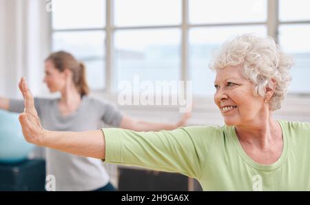 Portrait of senior woman practicing yoga au cours de gymnastique. Femme âgée s'étendant ses bras . Banque D'Images