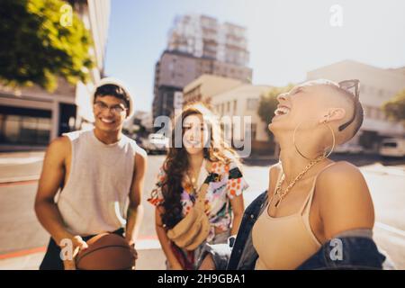 Trois amis ayant un bon moment ensemble à l'extérieur.Trois jeunes rient joyeusement en se tenant dans la ville.Groupe de la génération z amis h Banque D'Images