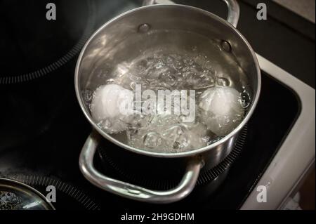 Deux œufs blancs sont bouillis dans une casserole. Banque D'Images